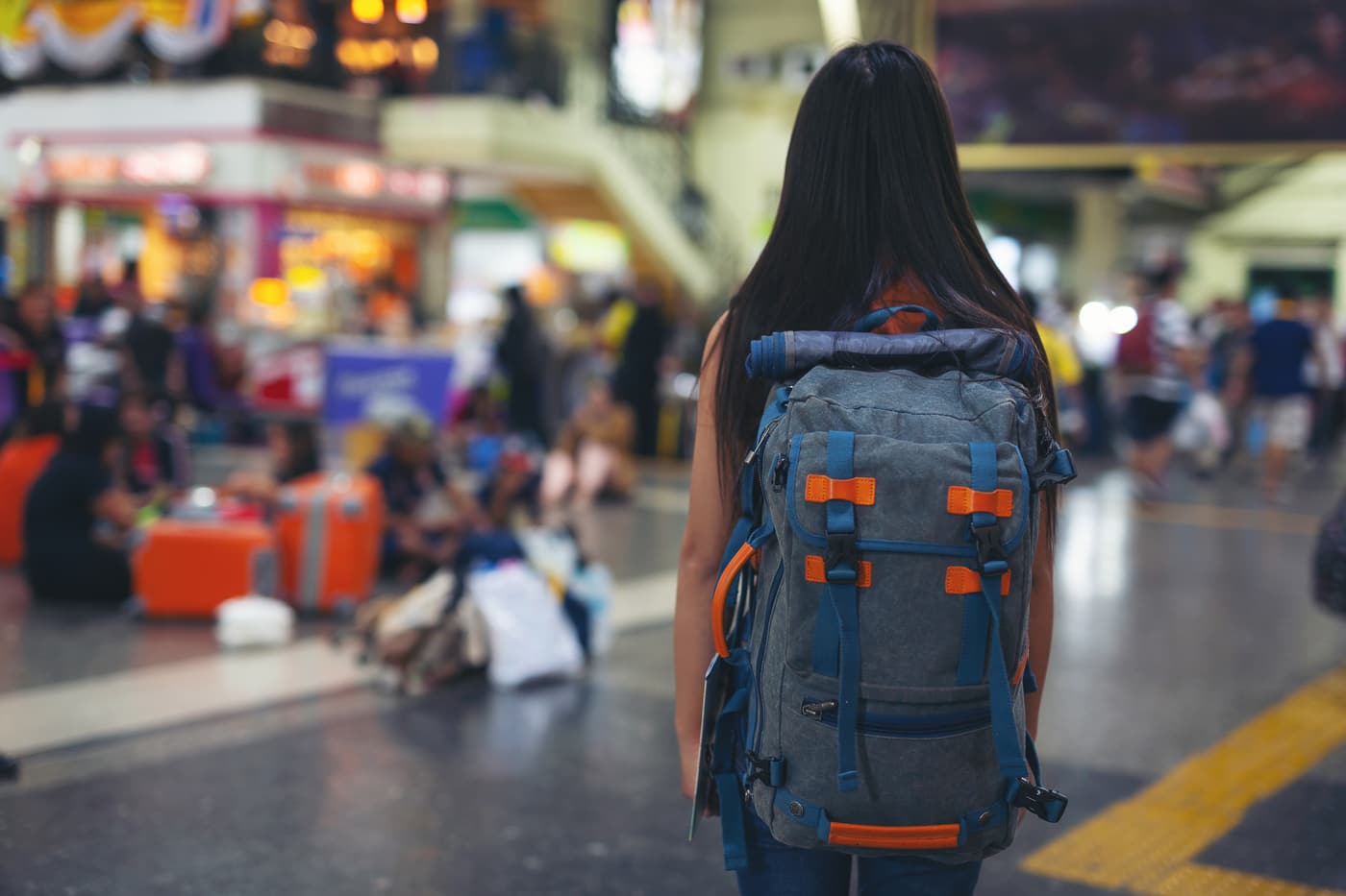 A student with a travel backpack standing in a busy train station